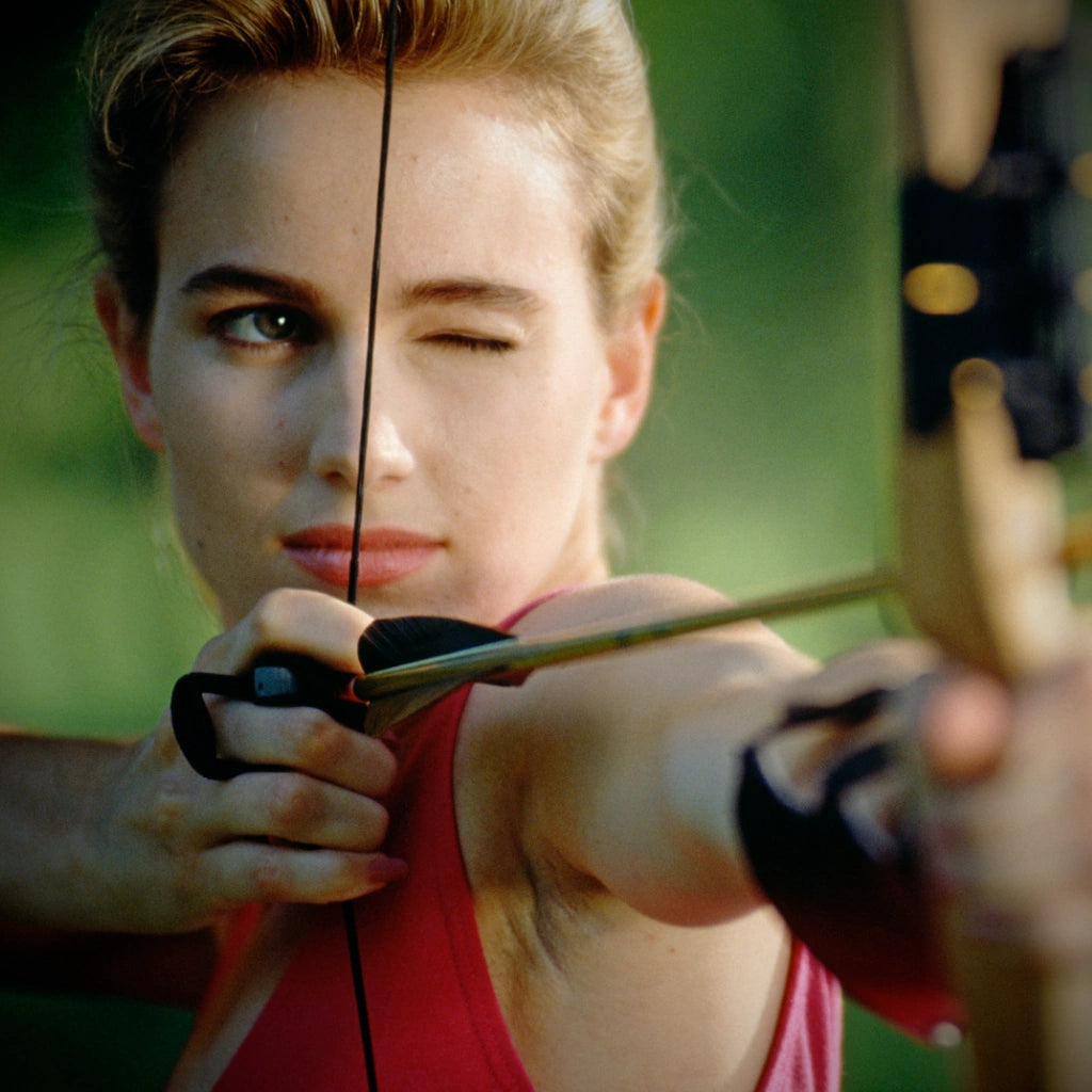 woman focusing on her bow shot, aiming the arrow