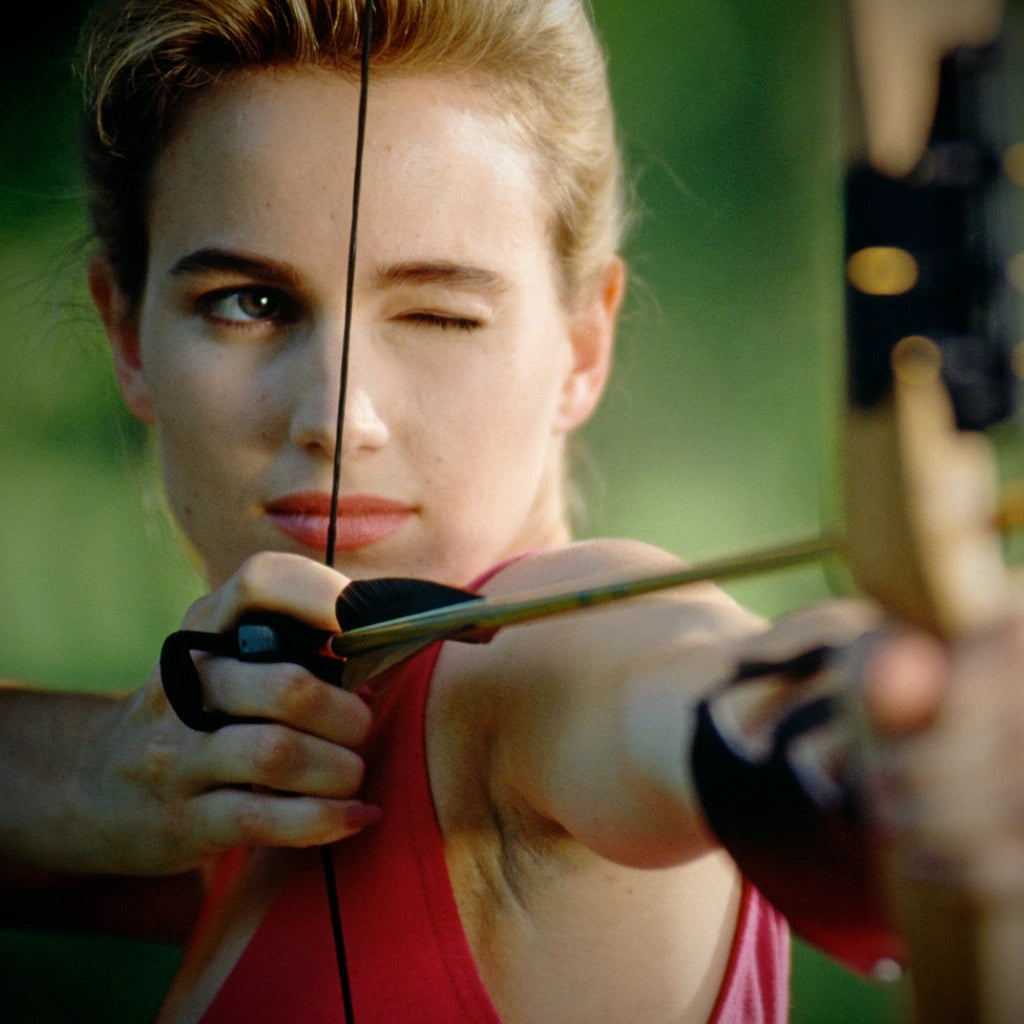 woman focusing on her bow shot, aiming the arrow 